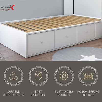 A white under-bed storage bed frame with natural wood slats, shown in a bedroom setting with a gray rug and wood floor. The image includes a StorX logo in the top-left corner and four feature icons at the bottom highlighting durable construction, easy assembly, sustainably sourced materials, and no box spring needed.
